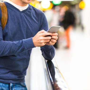 Sırt çantası uçuş bekliyor havaalanında cep telefonu tutan adamla