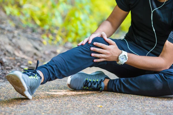 Atleta masculino que sufre de dolor en la pierna mientras hace ejercicio al aire libre — Foto de Stock