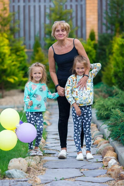 Piccole ragazze adorabili divertirsi con la nonna felice in estate giorno all'aperto — Foto Stock