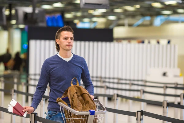 Young man with passports and boarding passes at the front desk at airport — Stock Photo, Image