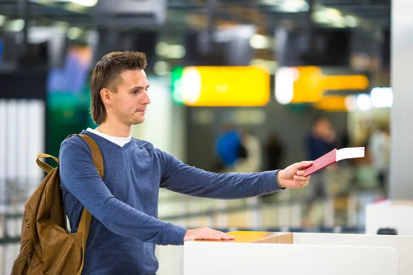 Junger Mann mit Pässen und Bordkarten an der Rezeption des Flughafens — Stockfoto