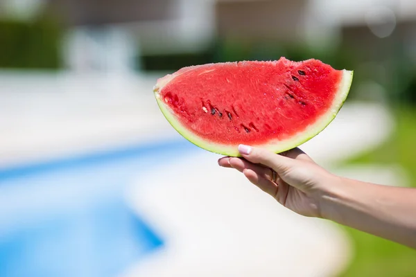 Primeros planos niña manos femeninas con sandía fondo piscina — Foto de Stock