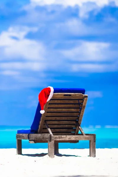 Red Santa hat on beach chair at tropical vacation — стоковое фото