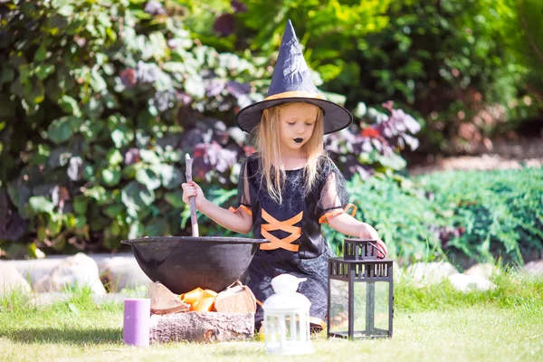 Menina adorável em traje de bruxa lançando um feitiço no Halloween. Doce ou travessura . — Fotografia de Stock