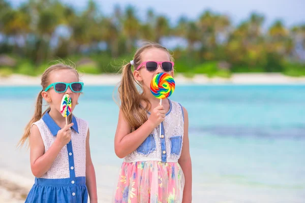 可爱的小女孩，与明亮的美味糖果，在白色的沙滩上 — 图库照片