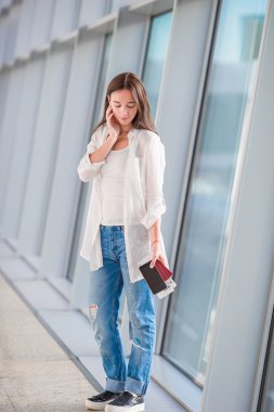 Havaalanında pasaportu olan bir kadın turist cep telefonuyla konuşuyor.