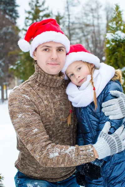 Glücklicher Vater und kleines Mädchen in Weihnachtsmützen mit Weihnachtsbaum im Freien — Stockfoto