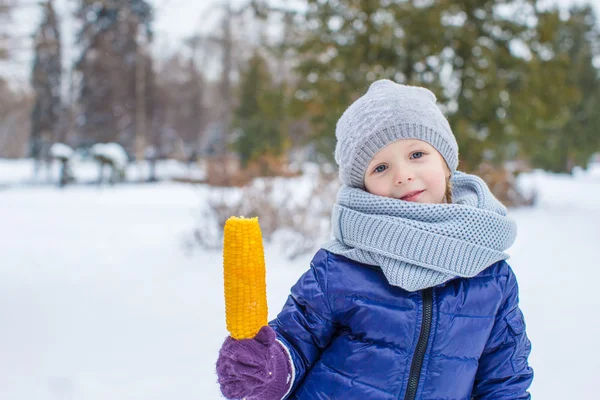 Little adorable girl eating tasty corn in winter day — Stock Photo, Image