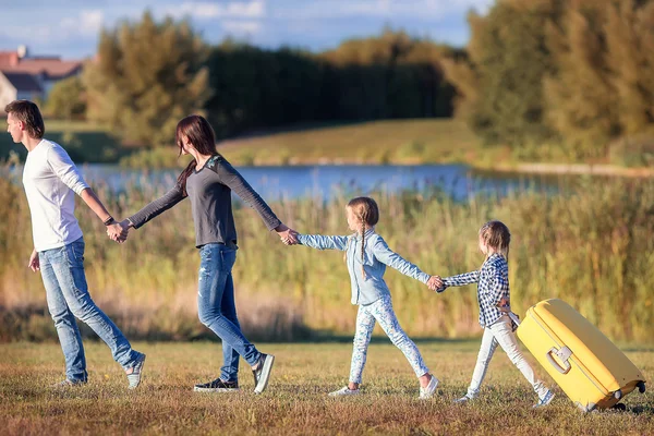 Happy family with suitcase walking outdoors — Stock Photo, Image