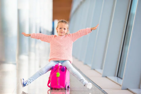 Bedårande liten flicka har kul på flygplatsen sitter på resväska — Stockfoto