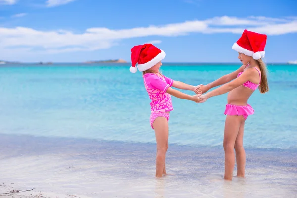 Маленькие очаровательные девочки в красных шляпах Санты на пляже тропического отдыха — стоковое фото