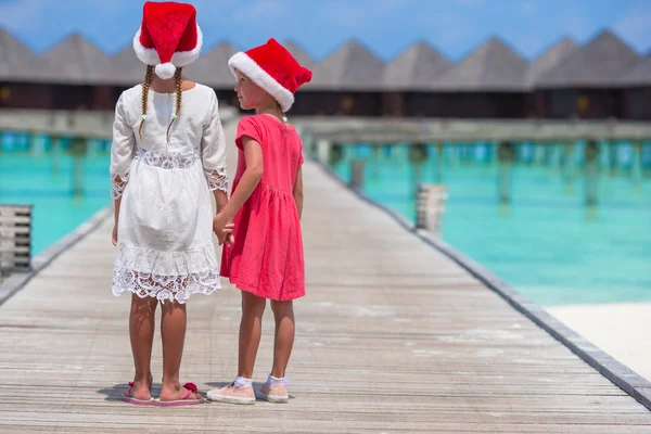 Kleine entzückende Mädchen in roten Weihnachtsmützen am Strand tropischen Urlaub — Stockfoto