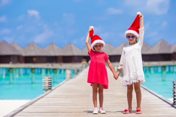 Kleine entzückende Mädchen in roten Weihnachtsmützen am Strand tropischen Urlaub — Stockfoto