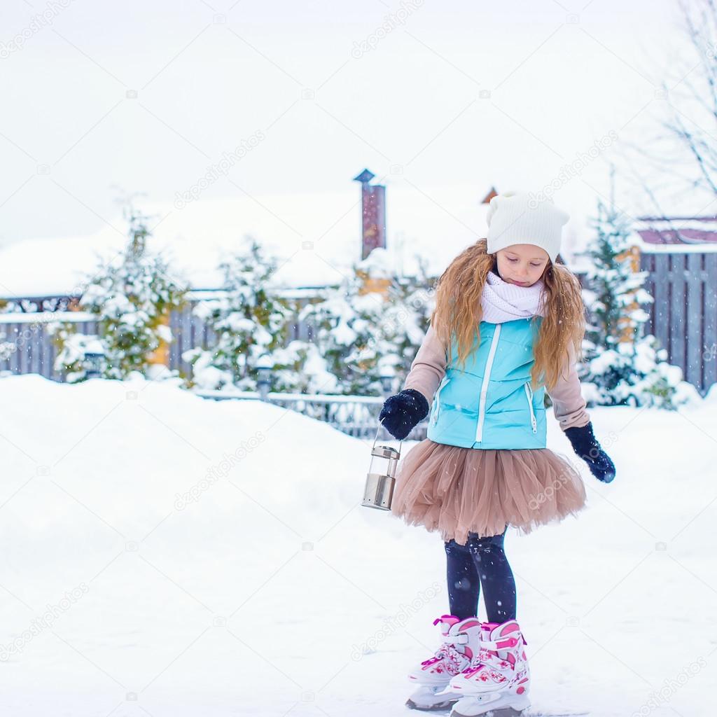 Adorable fashion little girl skating on the ice rink outdoors