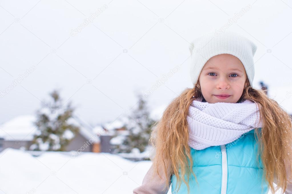 Portrait of little adorable girl with beautiful green eyes in snow sunny winter day