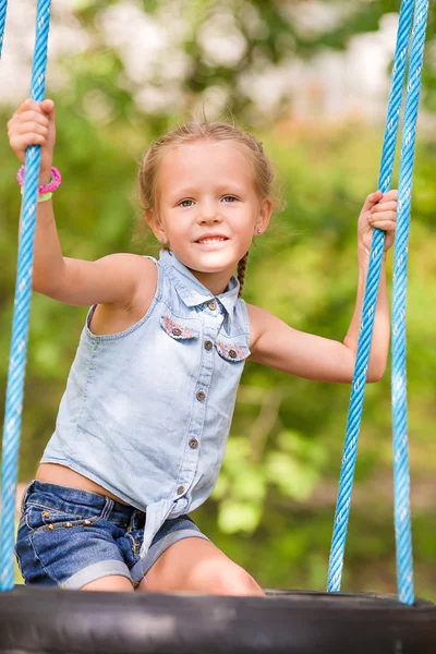 Adorable little girl having fun on a swing outdoors — Stock Photo, Image