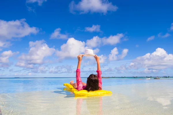 Ung, lykkelig kvinne som slapper av på en luftmadrass i sommerferien på stranden – stockfoto