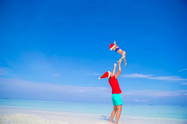 Kleines Mädchen und glücklicher Vater mit Weihnachtsmütze im Weihnachtsurlaub am Strand — Stockfoto