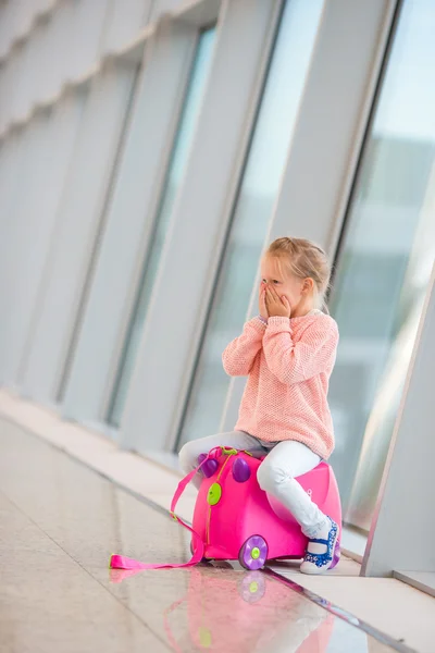 Adorable little girl in airport sitting on luggage waiting for boarding — Stock Photo, Image