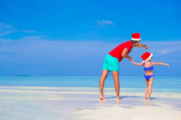 Mała dziewczynka i szczęśliwy ojciec w Santa Hat podczas plaży Christmas vacation — Zdjęcie stockowe