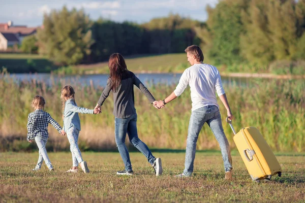 Happy family with suitcase walking outdoors — Stock Photo, Image