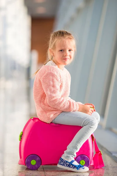 Adorable niña en el aeropuerto sentada en el equipaje esperando el embarque —  Fotos de Stock