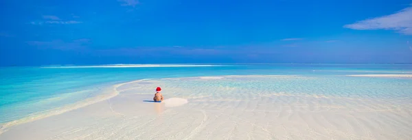 Little cute girl in Santa hat on white beach during vacation — Stock Photo, Image