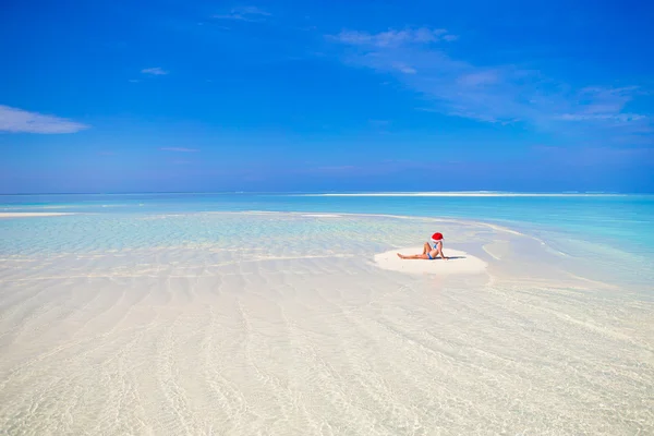 Little cute girl in Santa hat on white beach during vacation — Stock Photo, Image