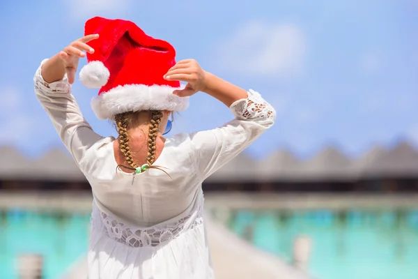 Little adorable girl in red Santa hat on white beach — Stock Photo, Image