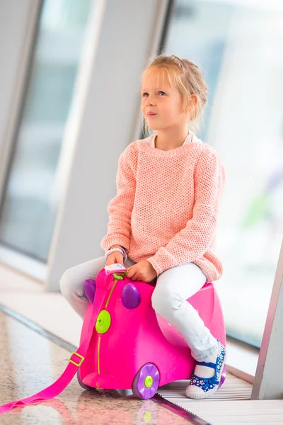 Adorable little girl in airport sitting on luggage waiting for boarding — Stock Photo, Image