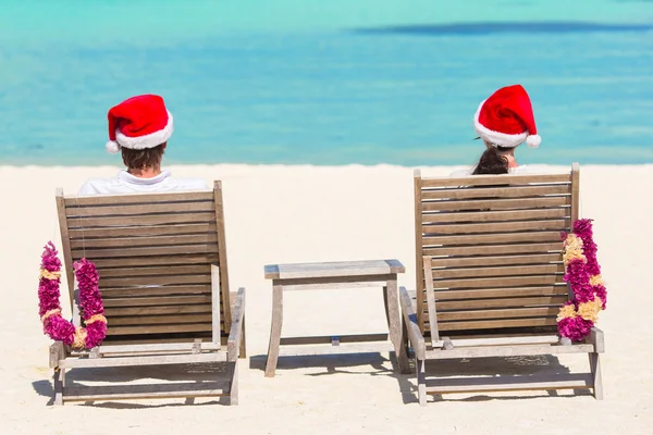 Молодая пара в шляпах Санта-Клауса отдыхает на тропическом пляже во время рождественских каникул — стоковое фото