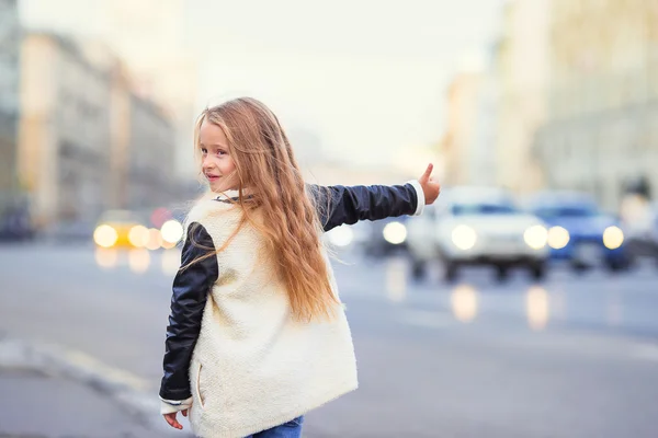 Очаровательная маленькая девочка получает такси на открытом воздухе в европейском городе — стоковое фото