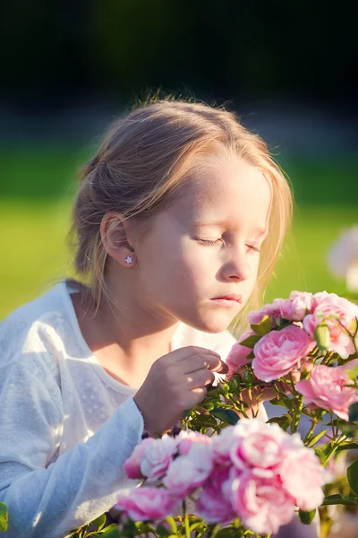 Lilla bedårande flickan att lukta färgglada blommor utomhus — Stockfoto