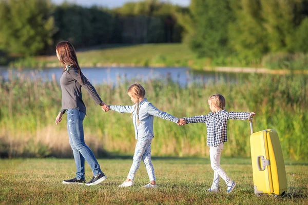 Familia feliz con maleta caminando al aire libre — Foto de Stock