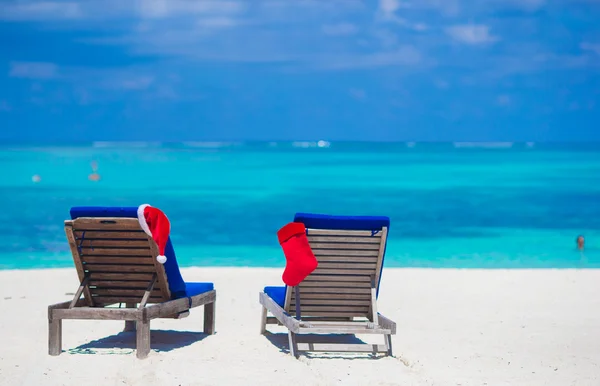 Red Santa Hat and Red Christmas stocking on beach loungers on tropical vacation — Stock Photo, Image