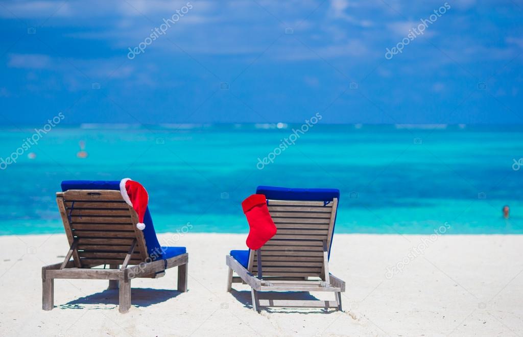 Red Santa Hat and Red Christmas stocking on beach loungers on tropical vacation