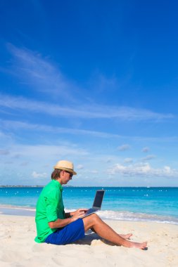 Beyaz tropikal plaj laptop ile genç adam