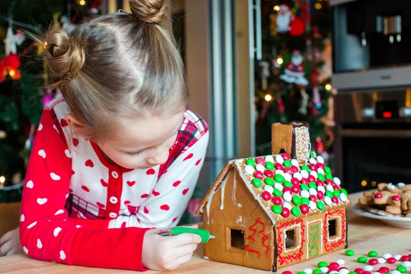Αξιολάτρευτο κοριτσάκι διακόσμηση μελόψωμο σπίτι για τα Χριστούγεννα — Φωτογραφία Αρχείου