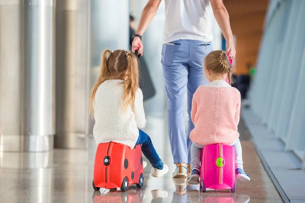 Adorables niñas con padre en el aeropuerto sentadas en la maleta esperando el embarque —  Fotos de Stock