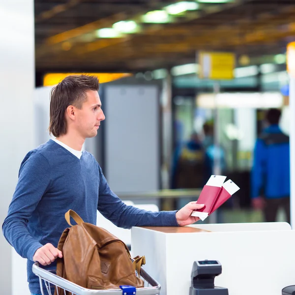 Joven con pasaportes y tarjetas de embarque en la recepción del aeropuerto —  Fotos de Stock