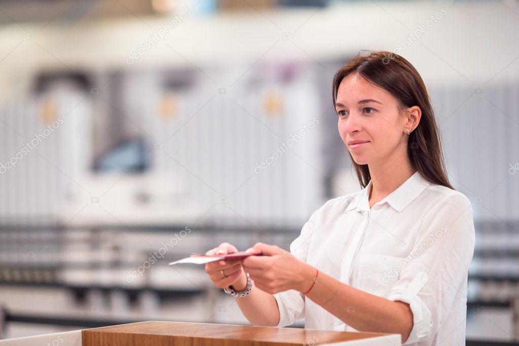Beautiful woman with passports and boarding passes at the front desk in airport