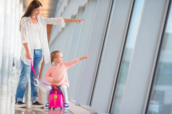 Familia feliz en el aeropuerto sentada en la maleta con tarjeta de embarque esperando el embarque — Foto de Stock