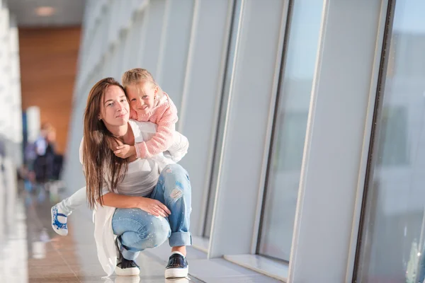 Familia feliz en el aeropuerto sentada en la maleta con tarjeta de embarque esperando el embarque —  Fotos de Stock