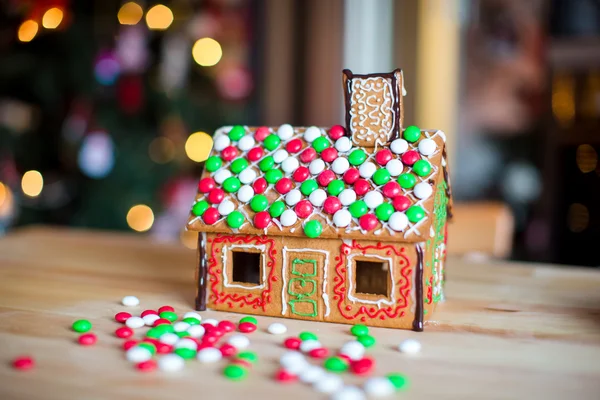 Perníková víla dům na pozadí jasného vánočního stromečku s věncem — Stock fotografie