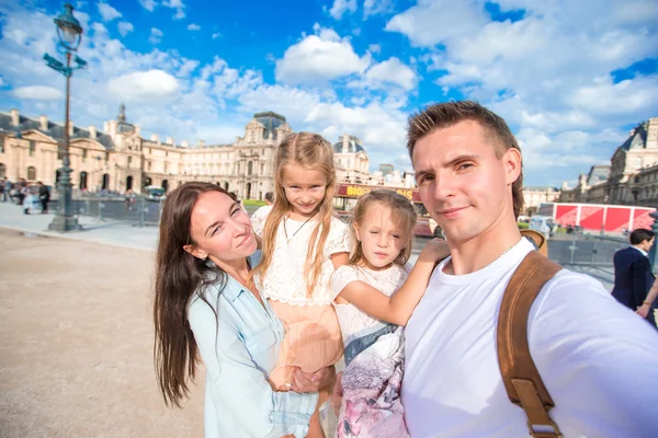 Jovem família feliz com mapa da cidade tomando fundo selfie famoso Louvre em Paris — Fotografia de Stock