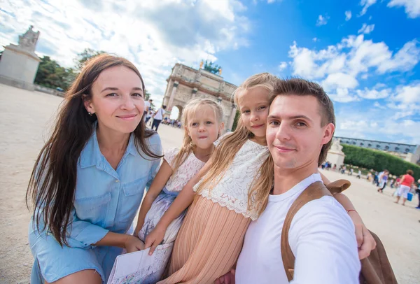 Feliz familia joven con mapa de la ciudad tomando selfie fondo famoso Louvre en París — Foto de Stock