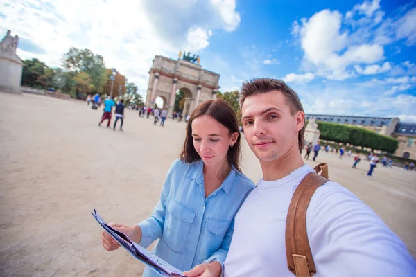 Romantyczna para młoda z mapą miasta biorąc selfie tło Luwr w Paryżu — Zdjęcie stockowe