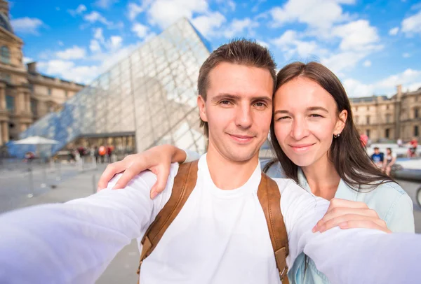 浪漫的年轻情侣，采取自拍照背景在巴黎著名的卢浮宫 — 图库照片