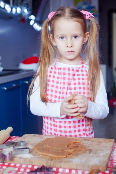 Kleines süßes Mädchen backt Lebkuchen für Weihnachten in der heimischen Küche — Stockfoto