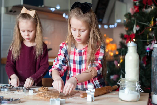 Маленькие девочки пекут пряничное печенье на Рождество на домашней кухне — стоковое фото